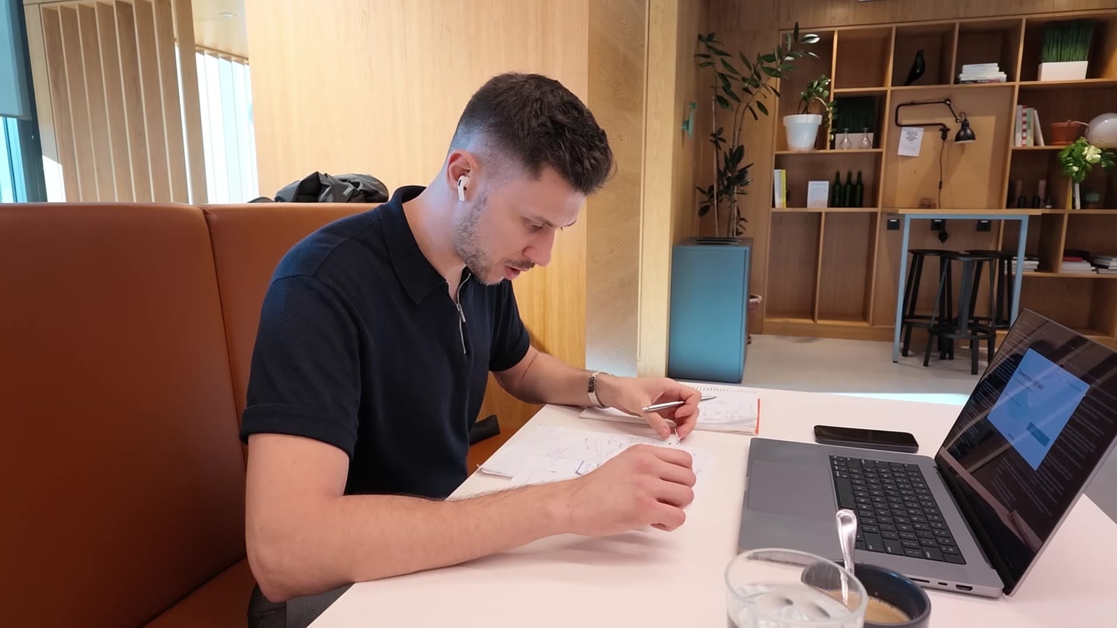 Bartek pisze w notesie przy laptopie w coworkingu